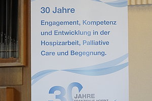 Roll-up mit dem Logo des Franziskus-Hospiz-Zentrums Hochdahl und dem Text '30 Jahre Engagement, Kompetenz und Entwicklung in der Hospizarbeit, Palliative Care und Begegnung.'
